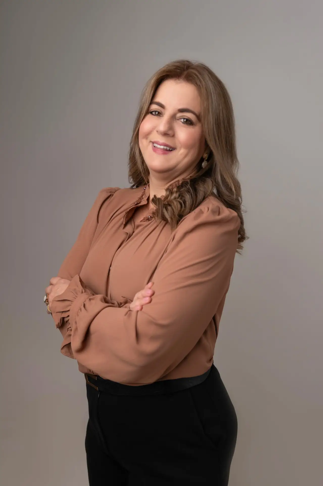Marcia Baldini, de braços cruzados, sorrindo, em retrato de estúdio