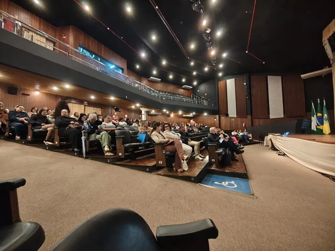Plateia de um teatro lotado assistindo a uma palestra sobre o Plano Nacional de Educação