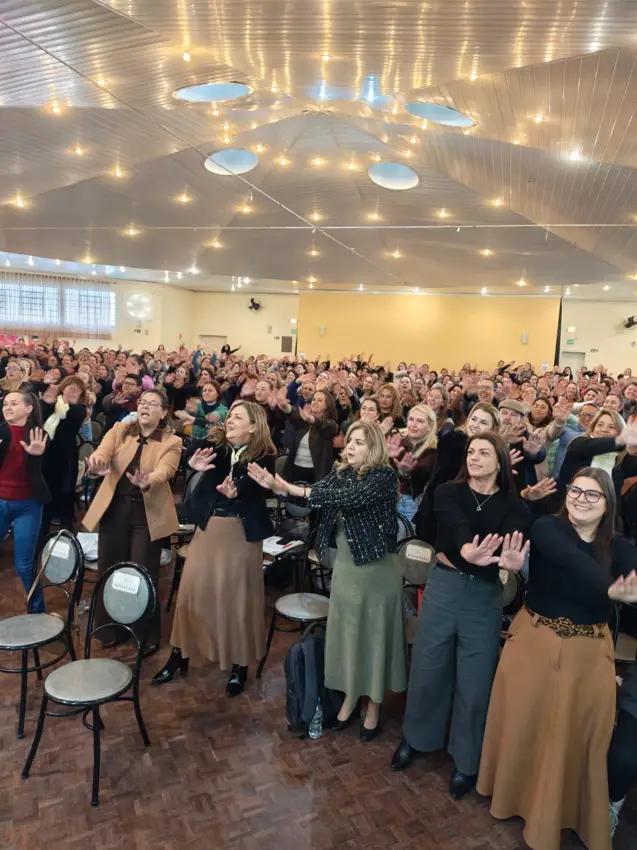 Plateia de educadores aplaudindo de pé numa palestra de Marcia Baldini
