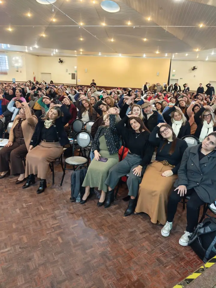 Plateia de educadores num salão durante uma palestra