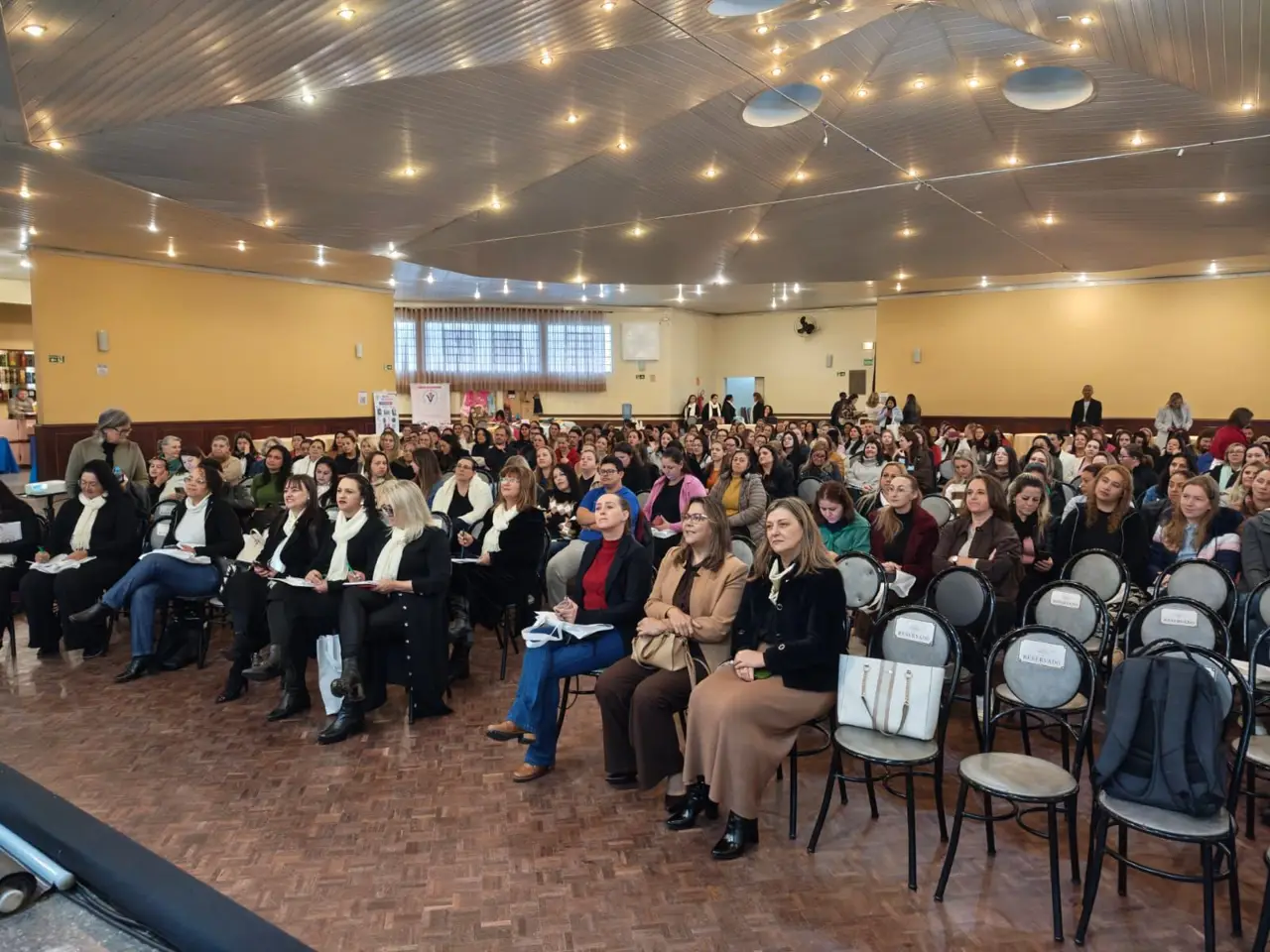 Salão cheio de educadores sentados durante uma formação
